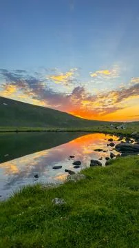 Dramatic sunset sky reflection in calm mountain lake at dusk Stock Photos