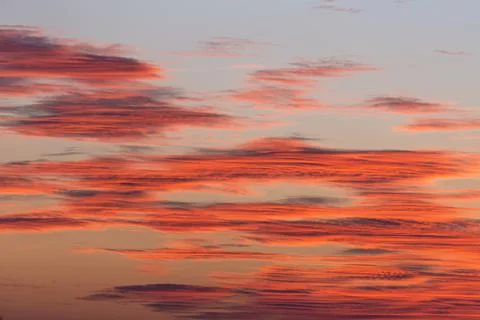 Dramatic sunset sky with saturated orange clouds with sunlight. Stock Photos