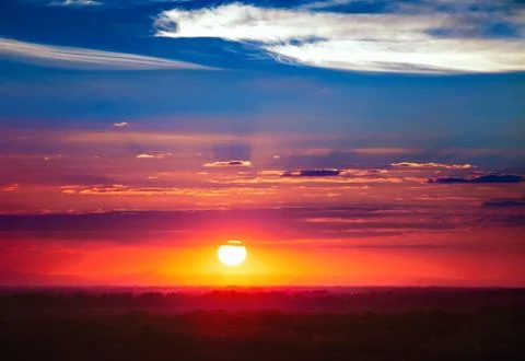 Dramatic sunset sky with sun and spindrift clouds Stock Photos