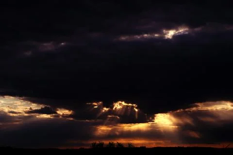 Dramatic sunset in the sky. The sun's rays pass through the clouds Stock Photos