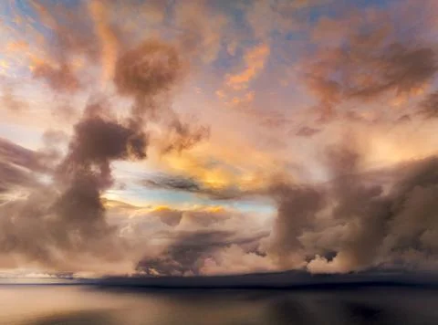 Dramatic sunset sky with vibrant clouds over a calm ocean horizon 写真素材