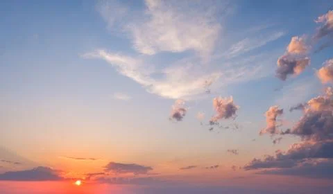 Dramatic sunset sky with vibrant colors and fluffy clouds over a serene horizon 写真素材