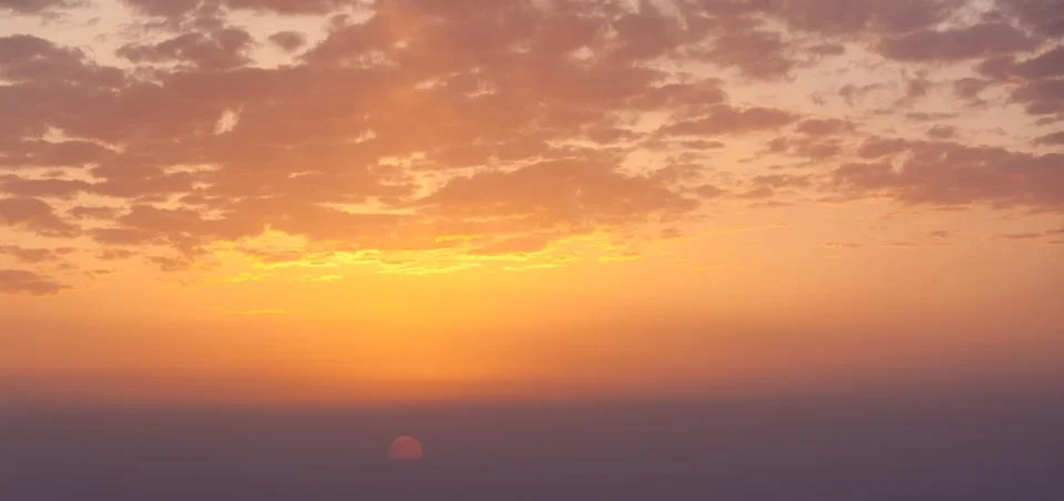 Dramatic sunset sky with vibrant colors and soft clouds across the horizon Fotos de archivo