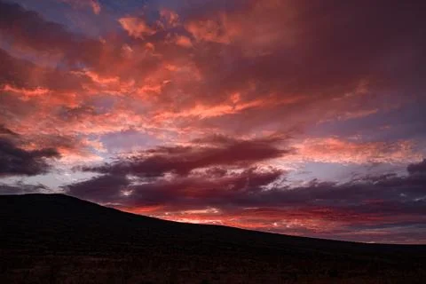 Dramatic Sunset Sky with Vibrant Red and Purple Clouds Over Mountain Landscape Stock Photos