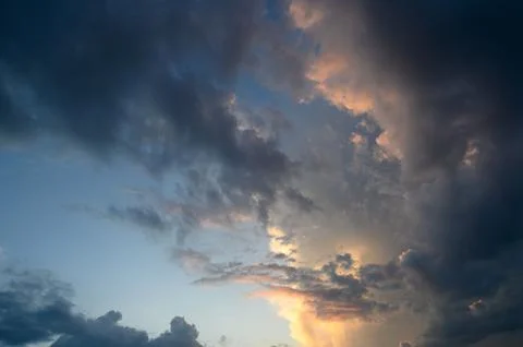 Dramatic sunset skyscape featuring dark storm clouds and warm golden illumi.. Foto stock