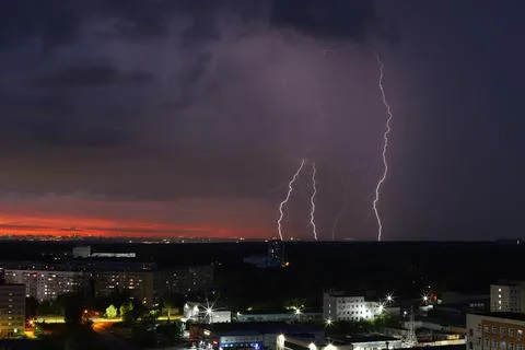 A dramatic sunset with storm clouds and rain over the cityscape Stock Photos