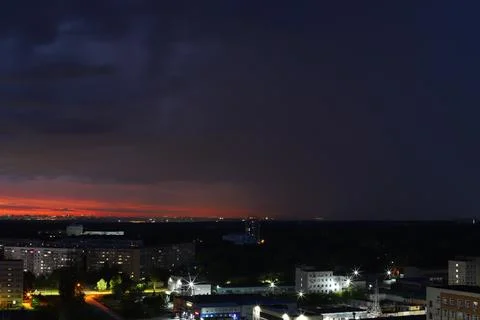A dramatic sunset with storm clouds and rain over the cityscape Stock Photos