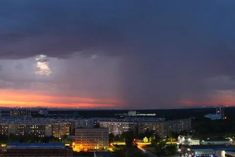 A dramatic sunset with storm clouds and rain over the cityscape Stock Photos