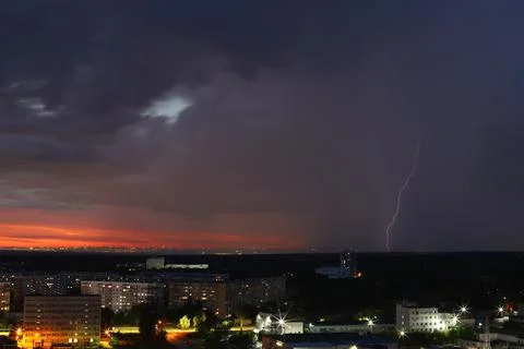 A dramatic sunset with storm clouds and rain over the cityscape Stock Photos