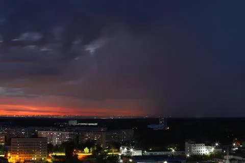 A dramatic sunset with storm clouds and rain over the cityscape Stock Photos