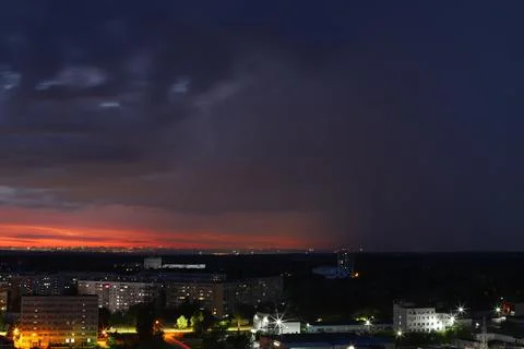 A dramatic sunset with storm clouds and rain over the cityscape Stock Photos