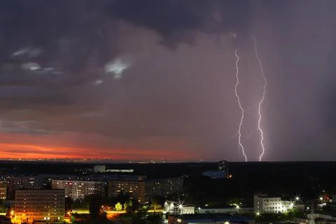 A dramatic sunset with storm clouds and rain over the cityscape Stock Photos