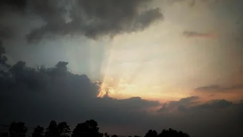 Dramatic Sunset with Sun Rays Breaking Through Clouds Stock Photos