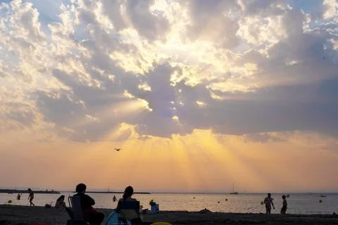 Dramatic sunset sun rays through the clouds on a beach Stock Photos