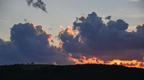 Dramatic sunset with thick clouds lit by the last rays of sunlight Stock Photos