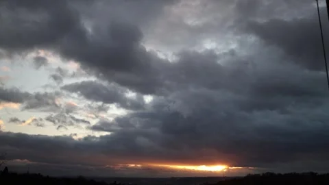 A dramatic sunset with thick, dark clouds covering the sky, revealing streaks of Stock Footage 293468051