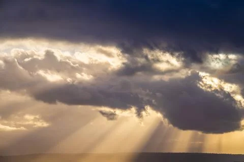 A dramatic sunset through the clouds over the ocean with rays of light Photos