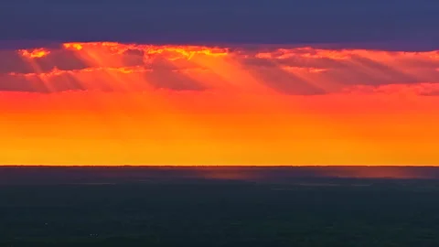 Dramatic sunset timelapse with golden beams pouring through a break in dark Stock Footage 323891451