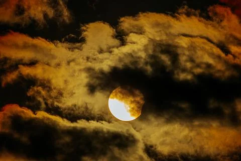Dramatic sunset view with partially obscured sun behind dark clouds, showca.. Stock Photos