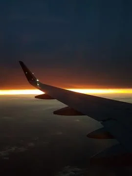 Dramatic sunset viewed from an airplane window with the aircraft wing silhouette Stock Photos