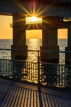 A dramatic sunset viewed from beneath a large bridge, showcasing a starburs.. Stock Photos