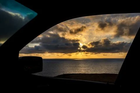 Dramatic sunset viewed through a car window over the ocean horizon Fotos de archivo