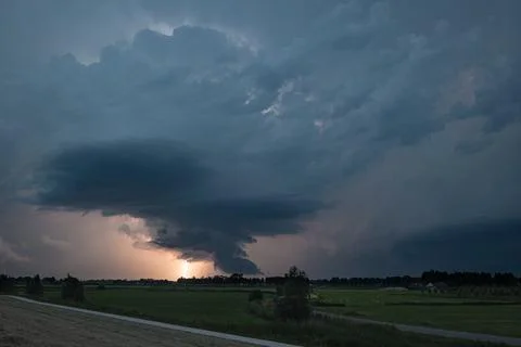 Dramatic supercell thunderstorm rolls over flat rural landscape at dusk Stock Photos