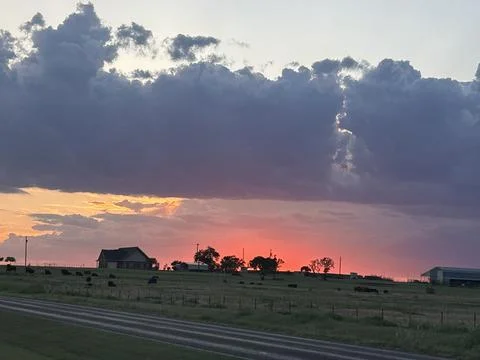 Dramatic Texas Sunset Beneath Storm Clouds Over Rural Farmland 스톡 사진