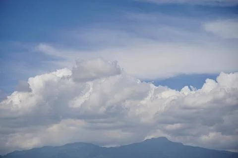 Dramatic thick cloud formations over mountain skies with sunlight Stock Photos