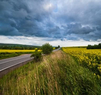 Dramatic thunderstorm cloud over countryside and spring yellow rapeseed field Stock Photos