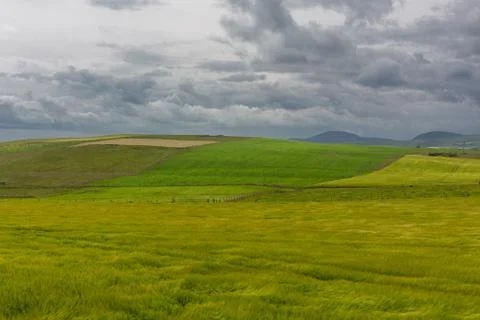 Dramatic thunderstorm clouds over farm green grass field Stock Photos