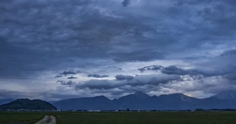 Dramatic time lapse of dark clouds moving over green pasture farming field Stock Footage 153992713