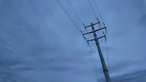Dramatic timelapse of moody clouds swirling over electricity pole at dusk Stock Footage 321665440