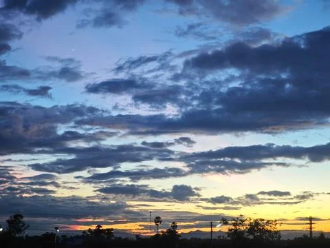 Dramatic twilight sky with dark clouds and golden sunset horizon. Stock Photos