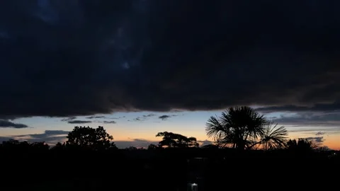 Dramatic twilight sky with dark moving storm clouds and silhouettes of tree.. Stock Footage 337751701