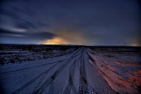 Dramatic twilight sky over a deserted gravel road stretching into the horiz.. Stock Photos