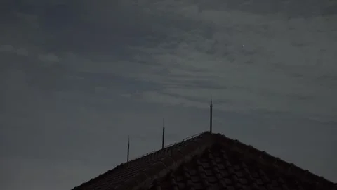 Dramatic twilight sky over a silhouetted rooftop with lightning rods in time Stock Footage 304662662