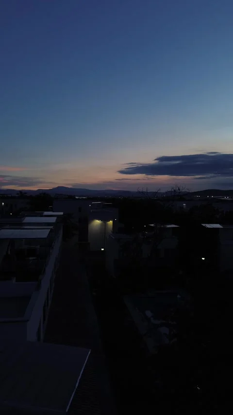 Dramatic twilight sunset tilt Up an tilt dawn pan rights   to twinkling roof lig Stock Footage 280014431