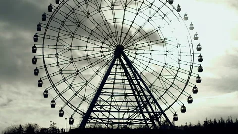 Dramatic uncomfortable silhouette of ferris wheel against dark greenish sky Stock Footage 246865453