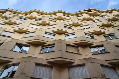 Dramatic upward view of a beige apartment building with angular, cantilever.. Stock Photos