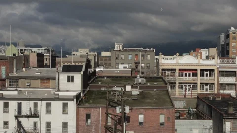 Dramatic Urban Cityscape, Sunlight on Low Brick Buildings, Dark Sky, 1080p HD Stock Footage 86884566