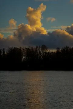 Dramatic vertical clouds above Daugava River and trees in Riga Stock Photos