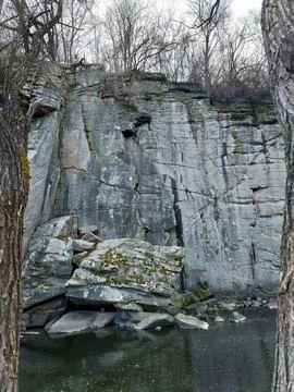 Dramatic vertical granite cliffs over a river in early spring forest Stock Photos