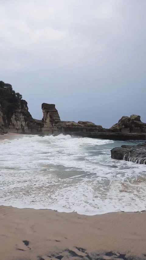 Dramatic vertical shot of a tropical rocky coastline with sea waves Stock Footage 337646252