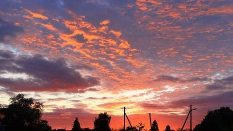 Dramatic vibrant red and orange clouds illuminated by a bright sunset over dark 스톡 사진