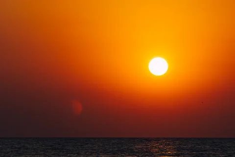 Dramatic vibrant sun over ocean with lens flare Stock Photos