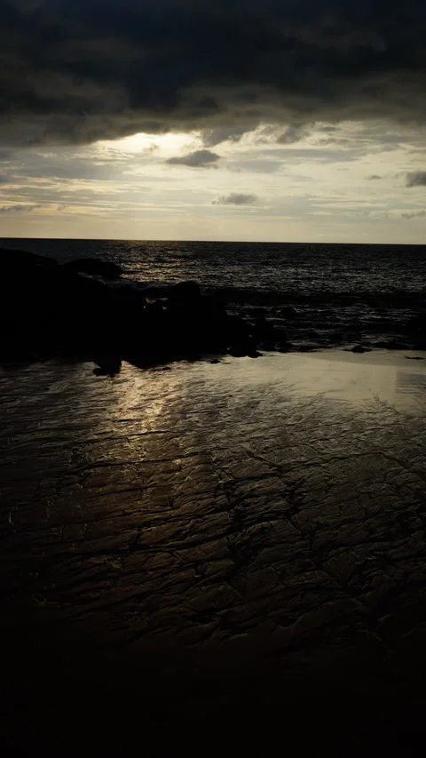 Dramatic view of a cloudy sky over a calm sea at twilight, with the setting sun Stock Footage 310493290