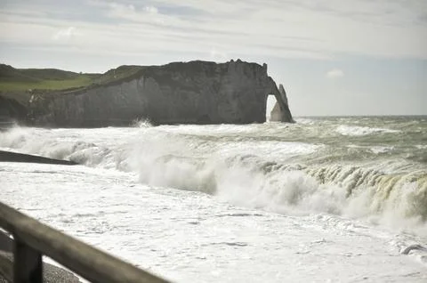 Dramatic view of Etretat cliff under bright sun and stormy skies Stock Photos