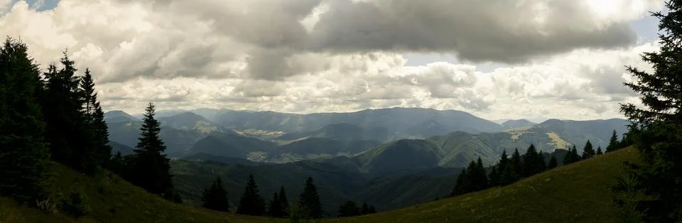 Dramatic view of expansive mountain landscape under cloudy sky with foreste.. Stock Photos
