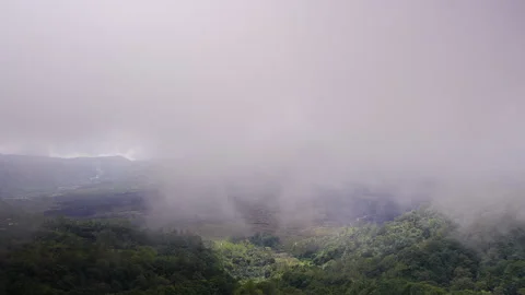 Dramatic View of Gunung Batur Volcano Partly Hidden by Low Clouds Above Lush Tro Stock Footage 336693492